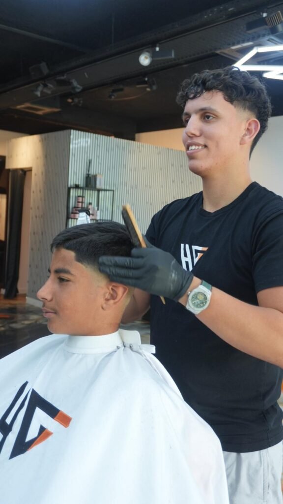 Barbier Hairitage terminant un dégradé sur un jeune client