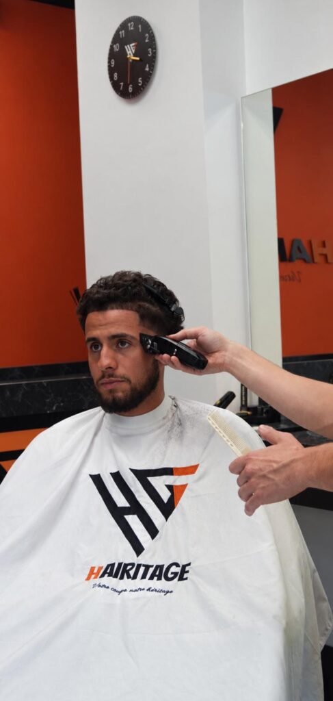 Barbier Hairitage réalisant un contour à la tondeuse